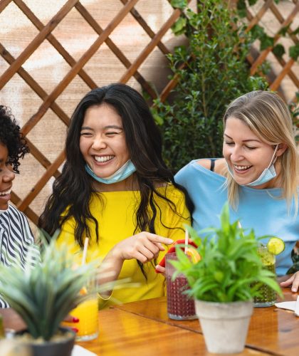 Multiracial friends watching on mobile smartphone while having healthy lunch in coffee brunch bar